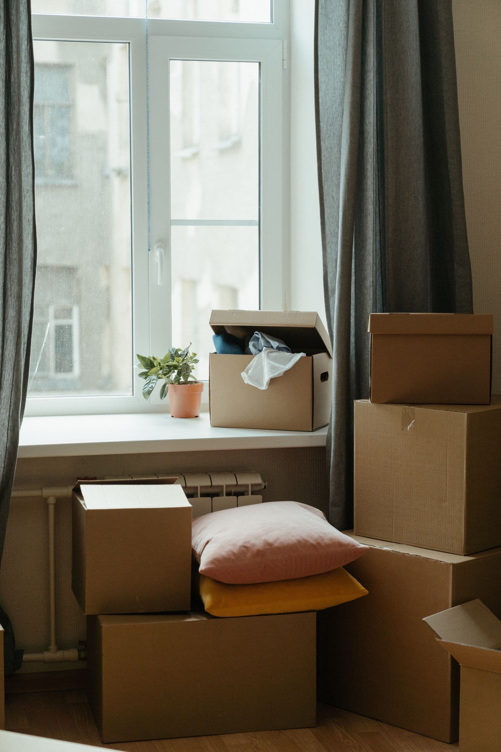 Stack of moving boxes in a sunlit, empty room